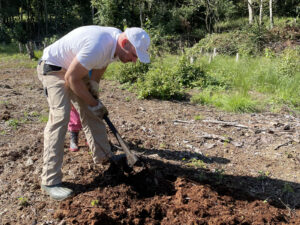 Mann mit Gartengerät bearbeitet den Boden