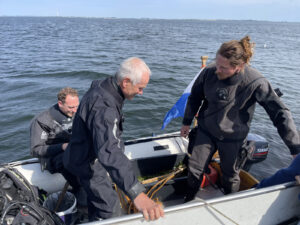 Drei Taucher steigen in ein Schlauchboot auf dem Meer ein.