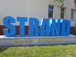 Große blaue Buchstaben bilden vor einer Hauswand das Wort "Strand"