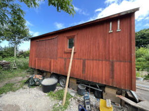 Bauwagen mit Arbeitsgerät vor seiner Seitenwand