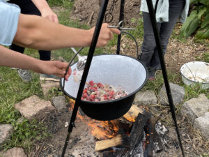 Ein Dreibein mit Kopftopf über einer Feuerstelle mit brennendem Holz