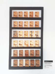 Kleine Holzblöcke in einem schwarzen Regal an der Wand symbolisieren Kohlenstoffspeicher in Form von Zigarettenpackungen