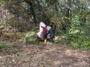 Zwei Personen schütten Gehölz auf einen großen Haufen