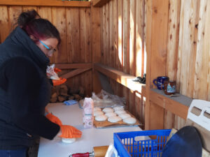 Eine Frau schaut auf den Backtisch in einem Holzstand