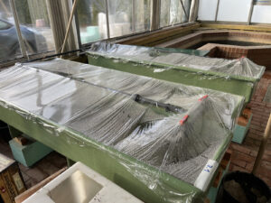 Plastikfolie über Wasserbecken mit Seegras als Verdunstungsschutz