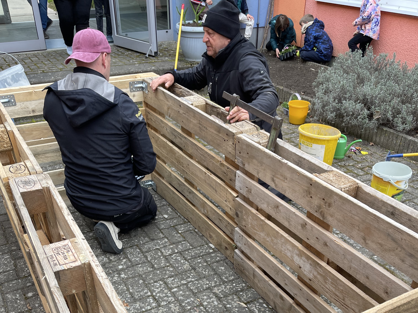 Zwei Personen an Euro-Paletten als Grundgerüst für ein Hochbeet