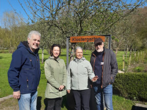 Vier Menschen stehen im Garten