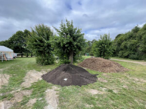 Ein Haufen mit Muttererde und ein Haufen mit Holzhack auf einer Wiese