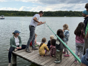 Kinder und Erwachsene auf einem Steg am See